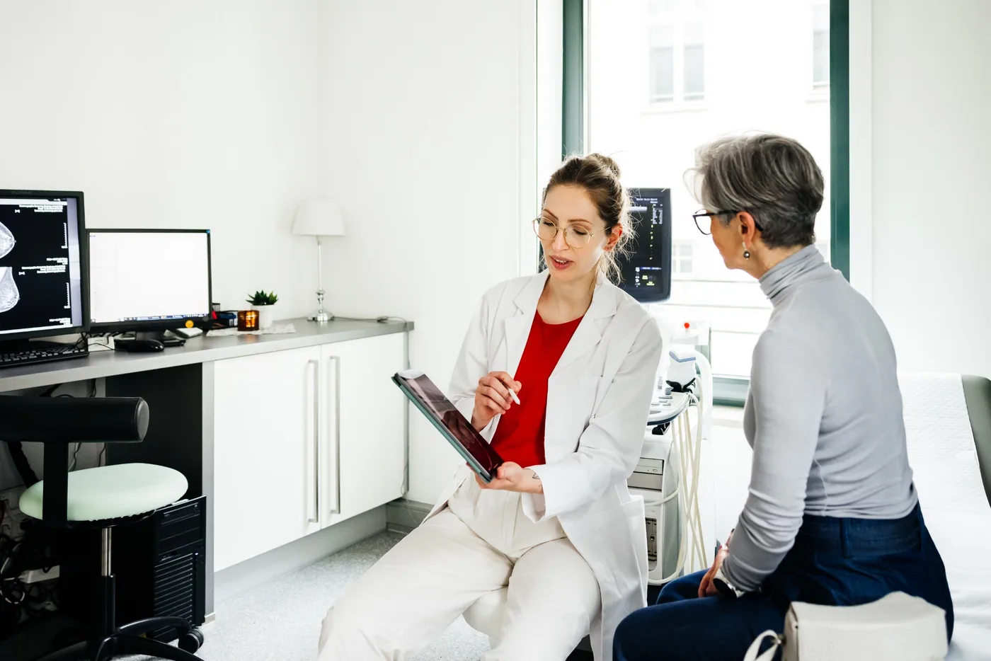 Ärztin erklärt einer Patientin etwas an einem digitalen Gerät